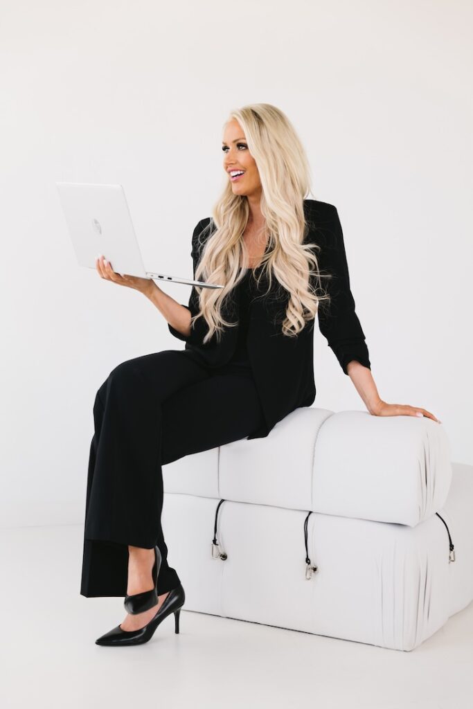 Modern brand photo of a female entrepreneur seated on a white couch in black attire, taken during a Fargo branding session.