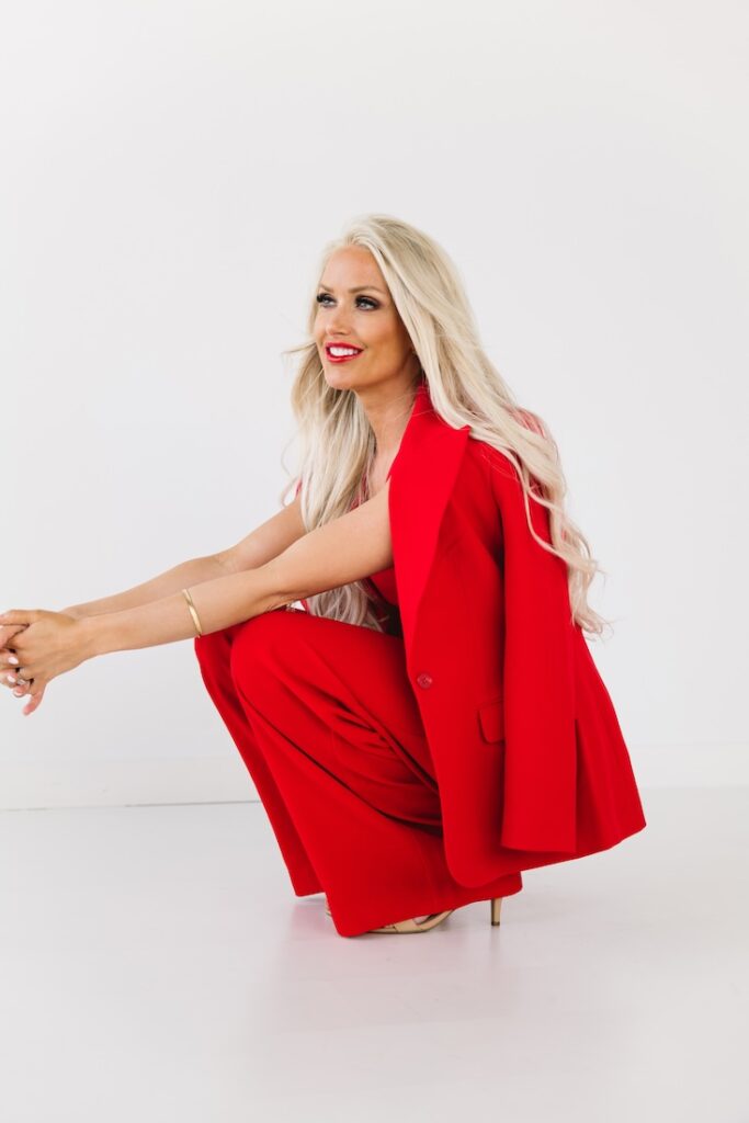 Bold, playful brand photo of a successful mortgage lender in bright red, seated against a clean backdrop.