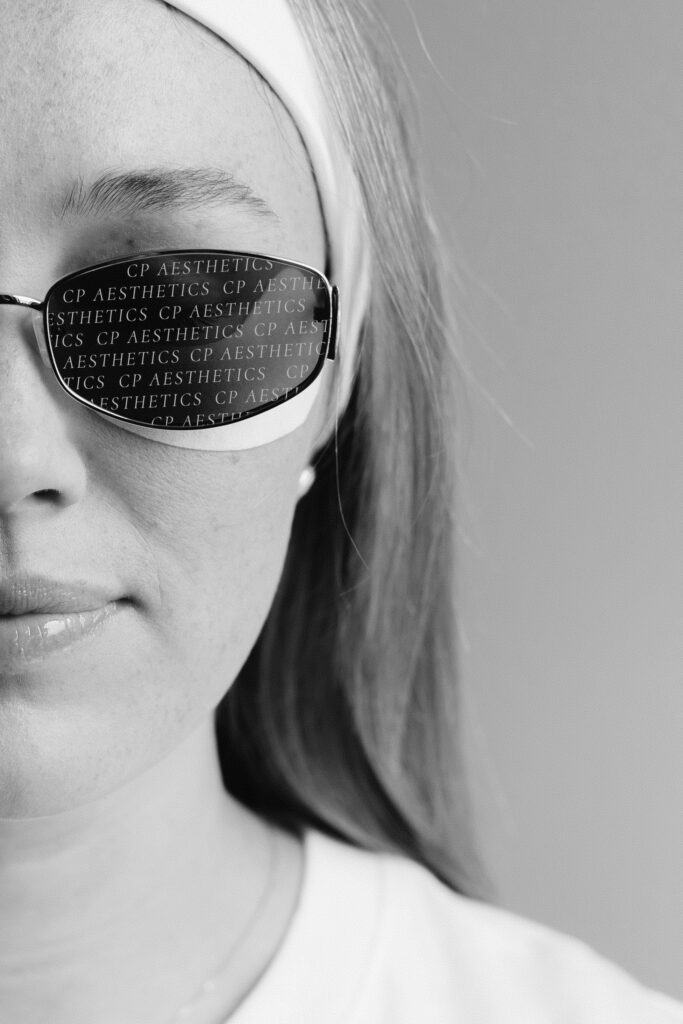 Black and white editorial spa brand photograph by Elisabeth Eden featuring a client wearing sunglasses with the business name reflected, highlighting luxury brand identity.